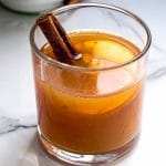 A glass of mulled apple cider with cinnamon stick