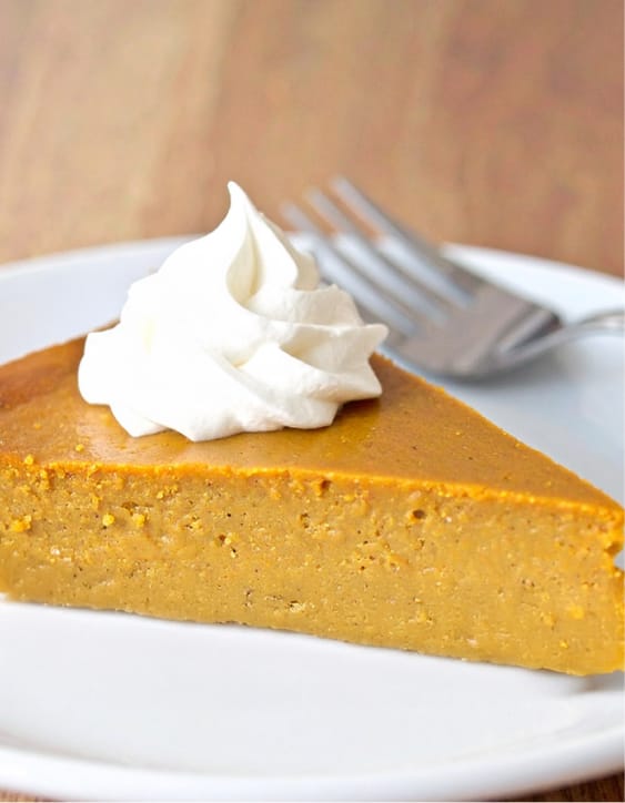 A slice of pumpkin pie has a whipped cream on top