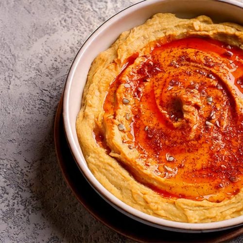 Harissa hummus recipe is garnish with parpika and sesame seeds
