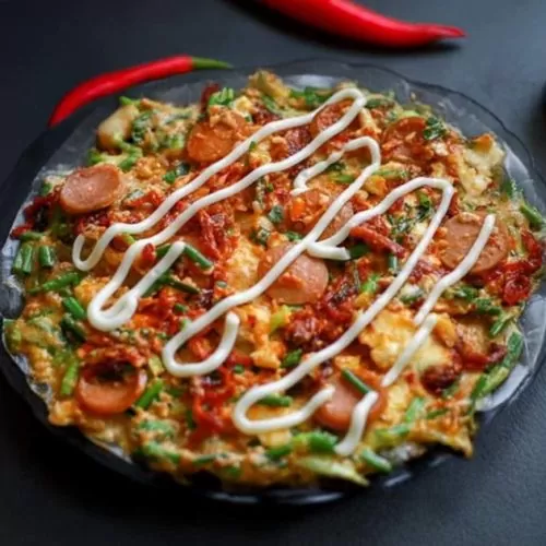 Vietnamese pizza is topped with egg, sausage, cheese, and green onions