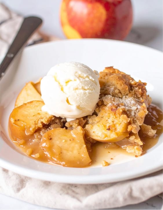 Apple cobbler is served with a scoop of ice cream