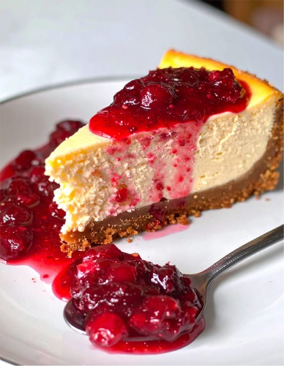 A slice of cranberry cheesecake with cranberry sauce spread on top
