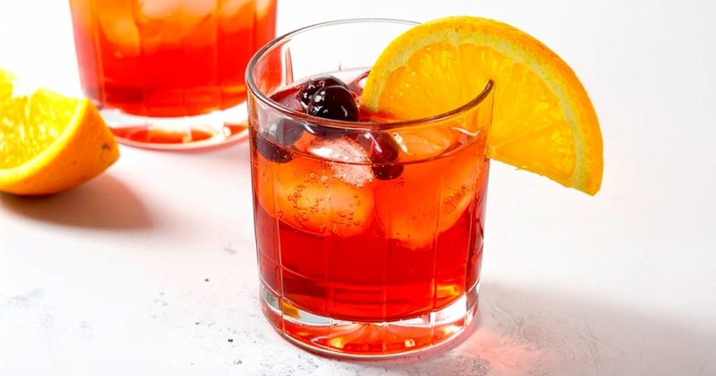 Non-alcoholic Cranberry Orange drink, garnished with an orange slice and fresh cranberries