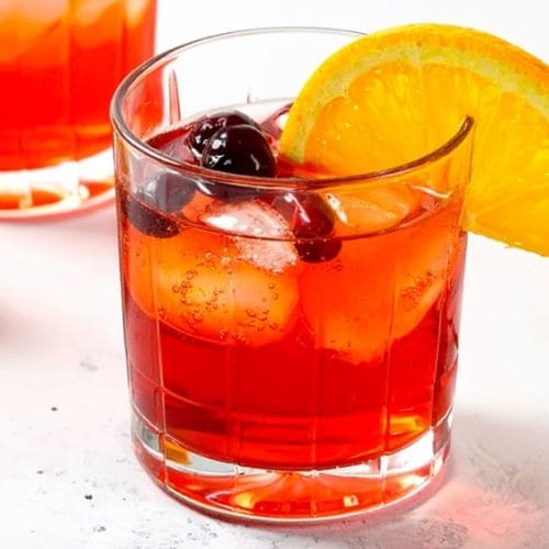 Non-alcoholic Cranberry Orange drink, garnished with an orange slice and fresh cranberries
